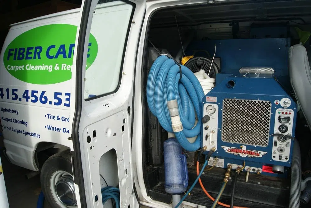 A van's open side door reveals cleaning equipment, including hoses and a machine, with "FIBER CARE Carpet Cleaning & Repair" visible. Serving Sonoma County, the company also offers professional upholstery cleaning services.